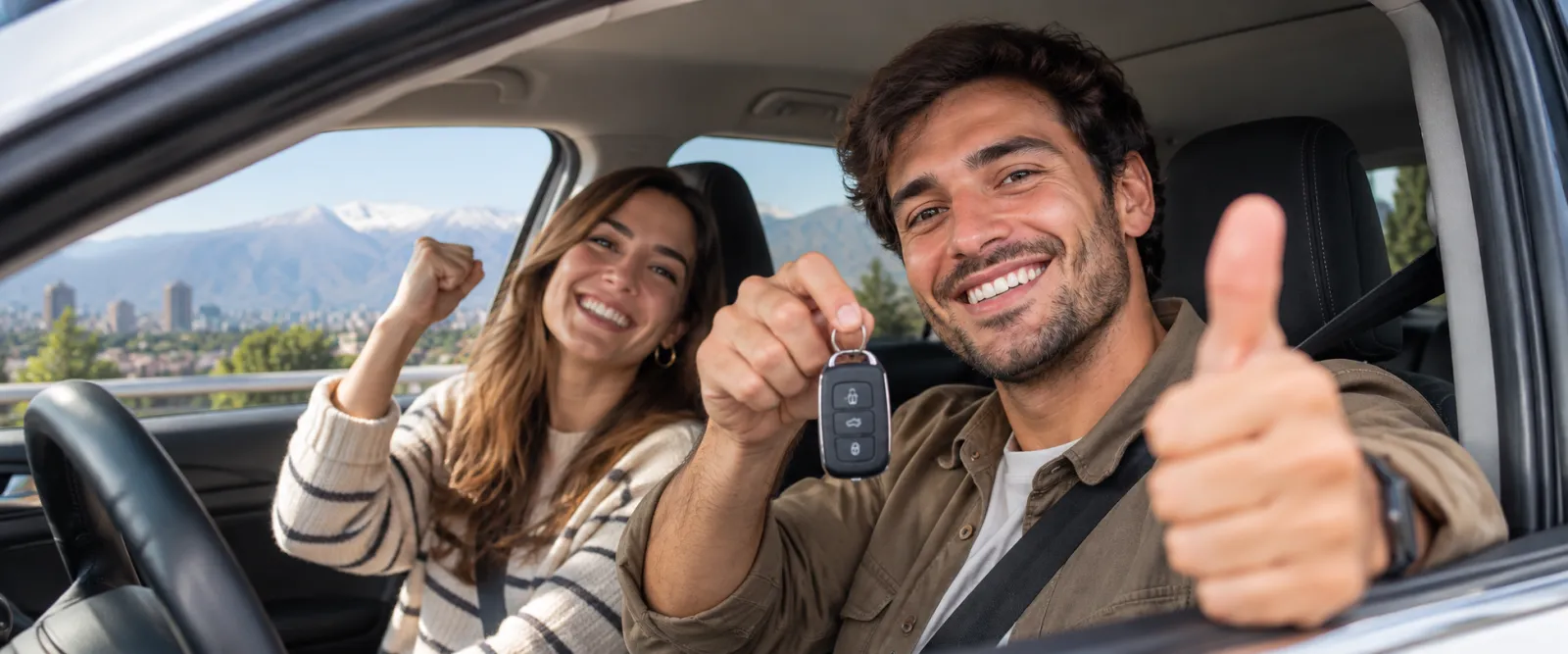 Pareja feliz dentro de su auto usado recién comprado, mostrando las llaves